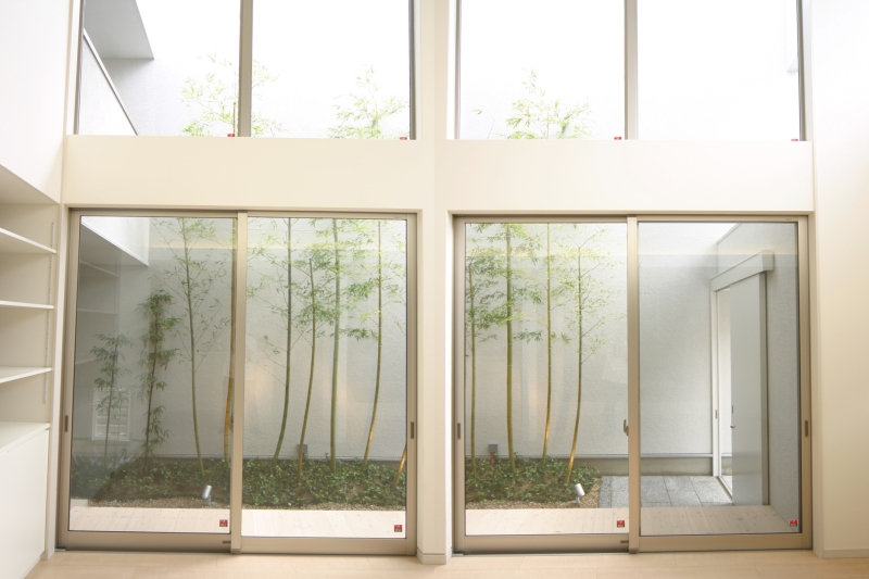 １階ＬＤＫの天井高5.3ｍの吹抜空間から、アプローチの竹林の庭を眺める。