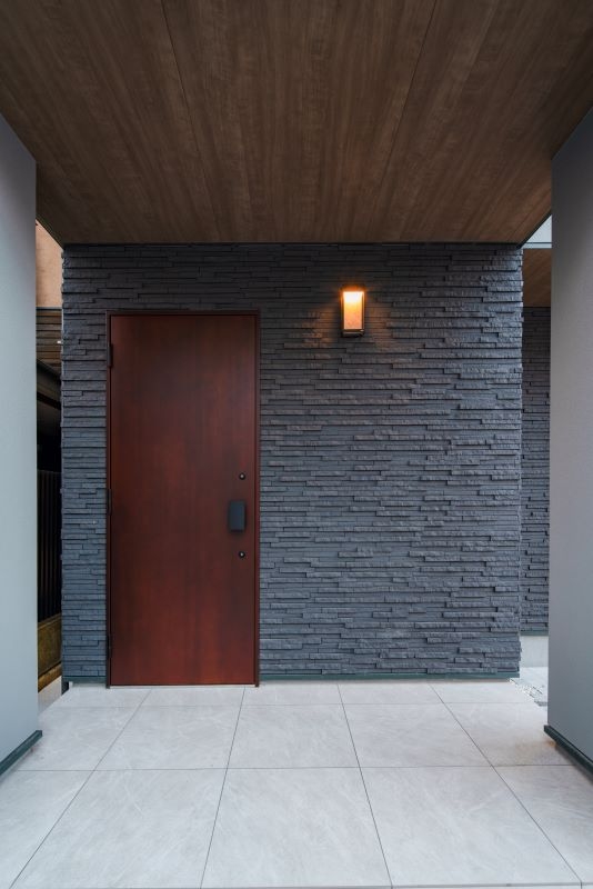 落ち着いた趣を演出したタイル張りの壁と鉄製の玄関扉