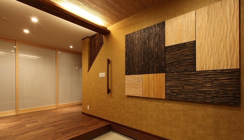 タペストリーを模した木のデザインウォールと格子・間接照明での奥行きをデザインした玄関